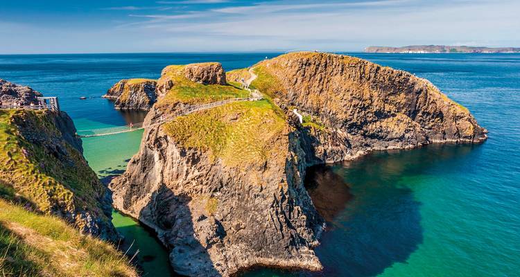 Un îlot rocheux relié par un pont au-dessus d'eaux turquoise.