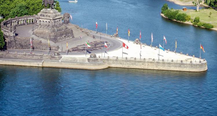 Monument historique au bord d'une rivière avec des drapeaux.