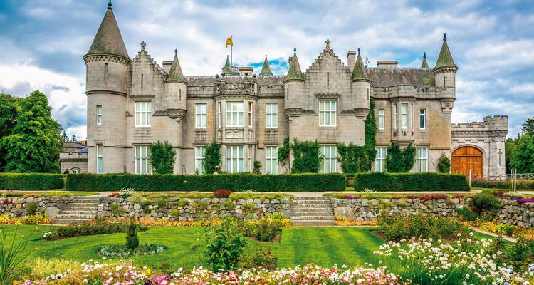 Historic castle with well-maintained gardens and blue sky above.