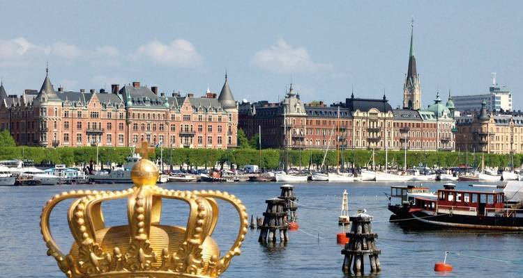 Golden crown sculpture with a city waterfront view.