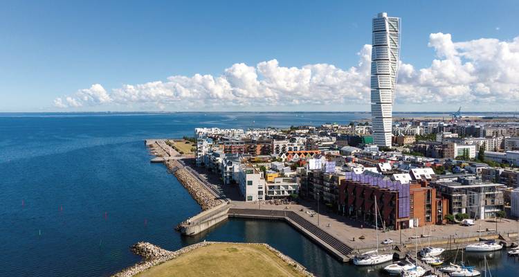 Coastal city view with a modern skyscraper and marina, likely in Sweden.