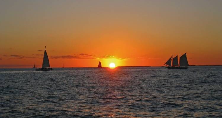 Sailboats on the ocean with a vibrant sunset.