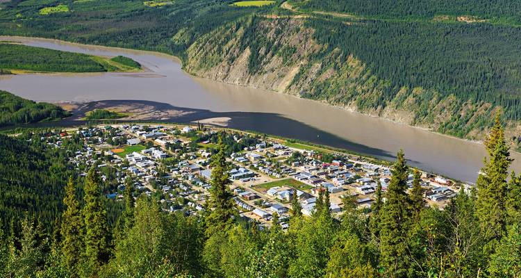 Rivière serpentant à travers un paysage boisé avec une ville.