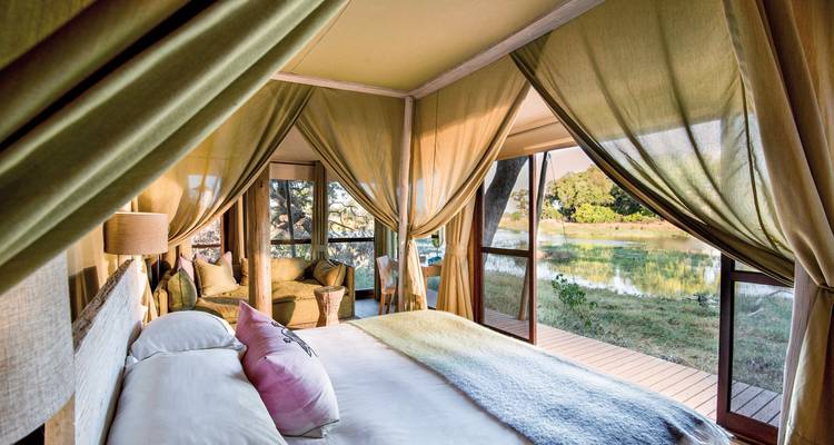 Intérieur de lodge safari chic avec vue sur le lac et mobilier luxueux.