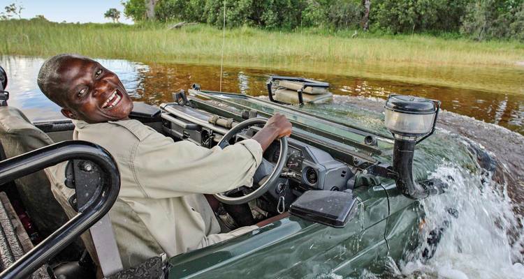 Expérience de safari joyeuse avec un guide conduisant à travers une eau peu profonde.
