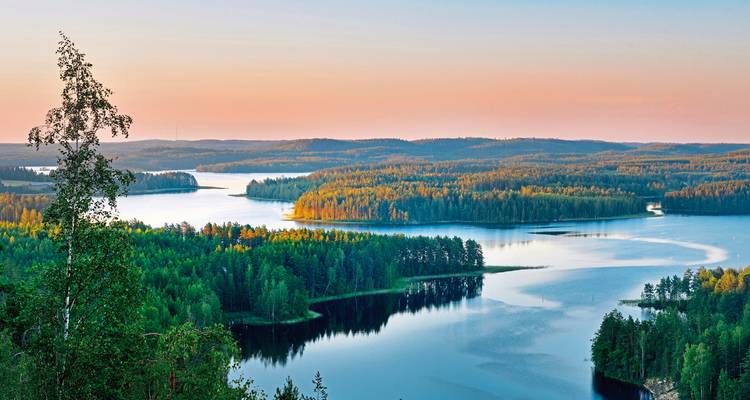 Weids uitzicht op meren en bossen tijdens zonsondergang.