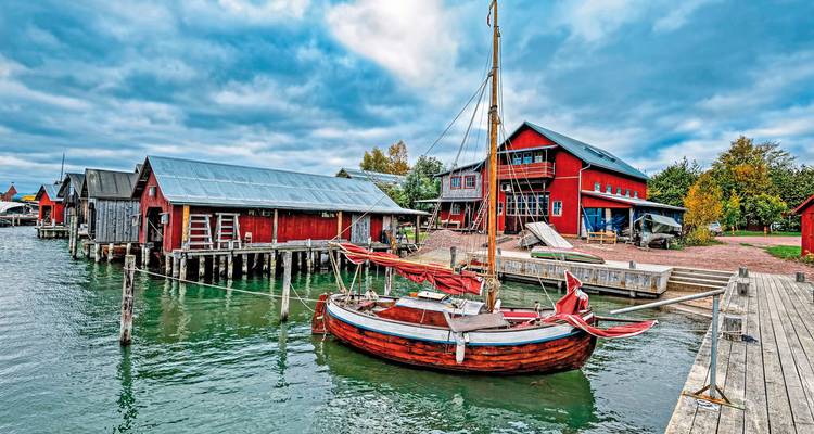 Traditioneel havenplaatje met een rode houten boot en gebouwen.