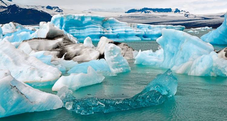 Icebergs flottant dans l'eau bleue avec des montagnes