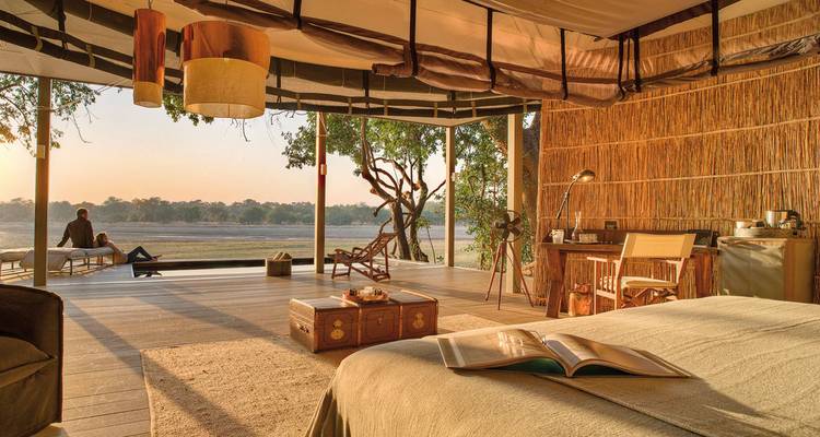 Chambre luxueuse avec vue ouverte donnant sur une rivière pittoresque, avec une personne profitant de la vue.