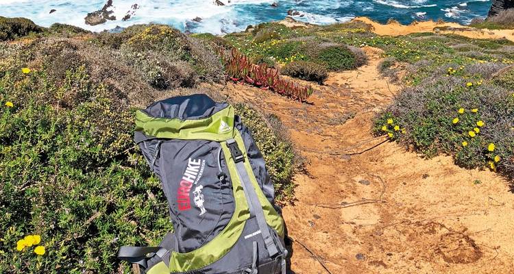 Paysage côtier avec un sac à dos sur un sentier.