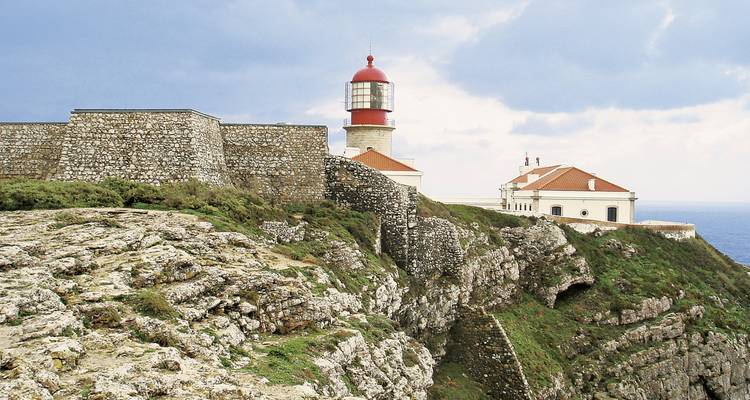 Phare sur une falaise avec un ciel nuageux.
