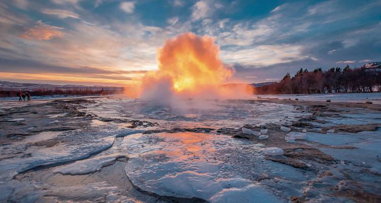 Geysir bricht mit farbigem Dampf bei Sonnenuntergang aus