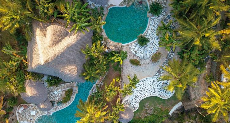 Aerial view of resort with pools and lush greenery.