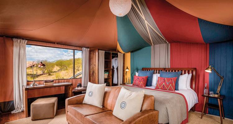 Modern tented suite with colorful interior and scenic view.
