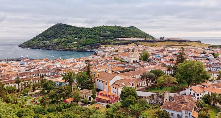 Ville côtière européenne avec des bâtiments colorés et de la verdure.