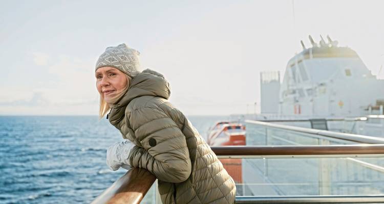 Woman enjoying the view from a cruise ship deck with the ocean and horizon visible.