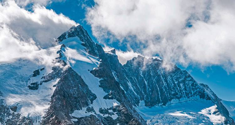 Snow-capped mountain peaks on a clear day with clouds.
