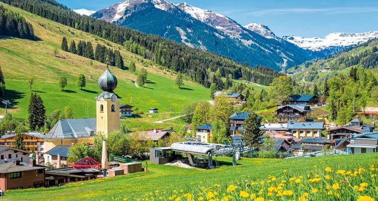 A village with a church and cable cars in a mountainous area.