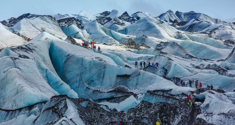 People exploring a glacier with icy crevices.