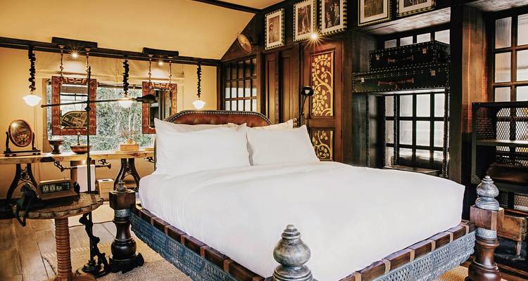 Stijlvolle hotelkamer met houten decor en groen uitzicht door de ramen.