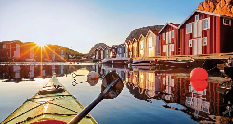 Vue au coucher du soleil de maisons en bois colorées au bord de l'eau avec un kayak.