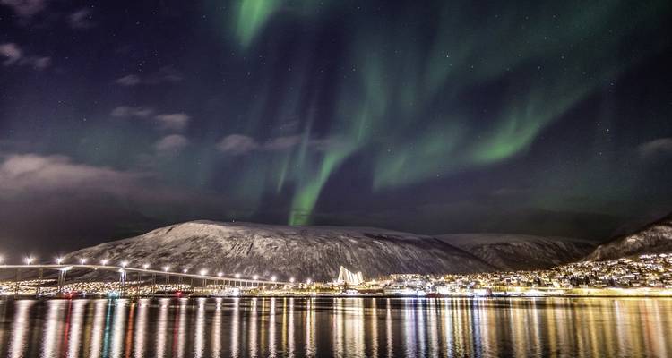Aurore boréale au-dessus d'une montagne enneigée et d'un pont