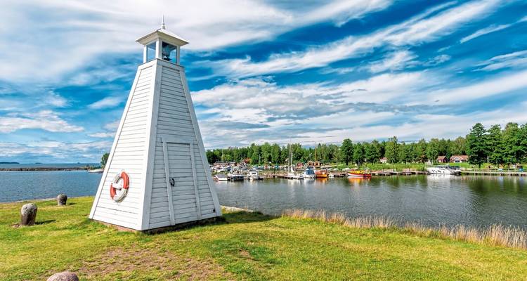 A white lighthouse by a marina with boats.