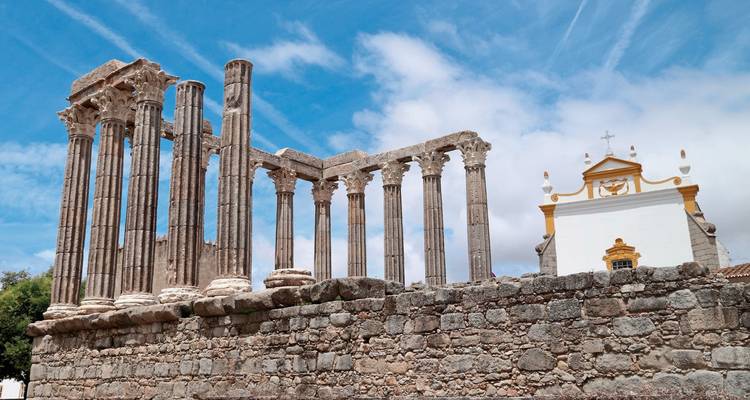 Ruines d'un ancien temple de pierre avec un bâtiment moderne derrière.