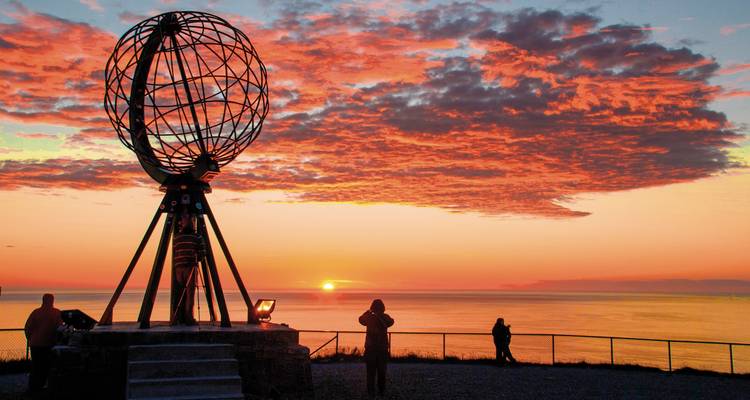 Globesculptuur bij zonsondergang met mensen die van het uitzicht genieten.