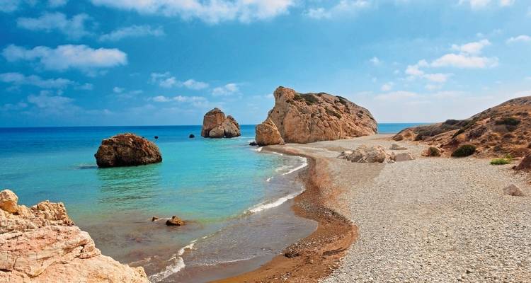 Kustrotsen en zandstrand met helder blauw water.