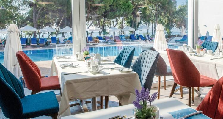 Elegante área de comedor con vista a una piscina y sombrillas.
