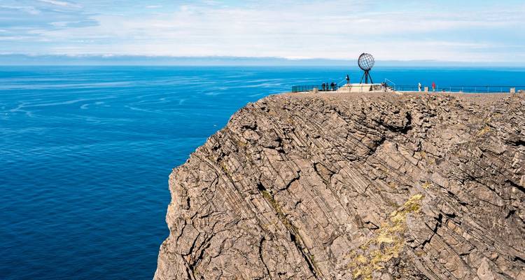 Ein Blick von der Klippe mit einer Globus-Statue und Touristen, die auf den Ozean blicken.