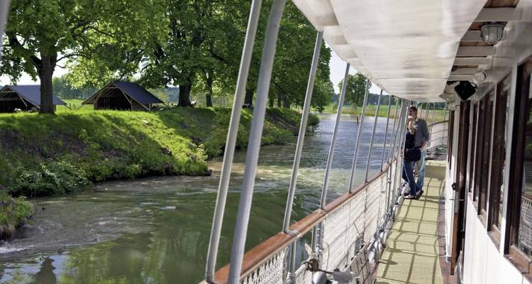 Vue sur le canal depuis un bateau avec des arbres et un paysage défilant