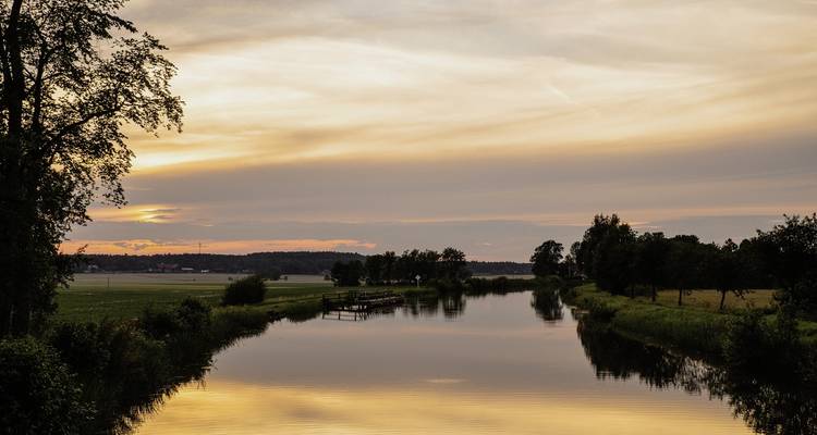 Coucher de soleil sur une rivière calme avec un environnement luxuriant