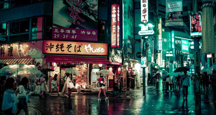 Night scene of a street with people walking under neon lights and rain.