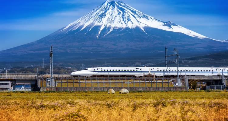 Mount Fuji with a high-speed train passing through fields.