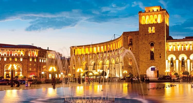 Fontein verlicht in de nacht op een stadsplein.
