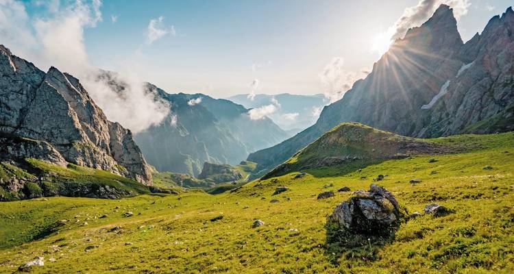 Schilderachtig uitzicht op een weelderige groene vallei met bergen en zonnestralen