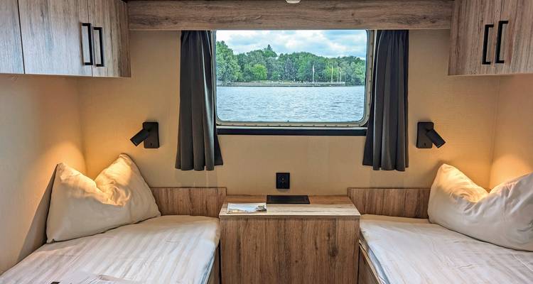 Intérieur de cabine avec lits jumeaux et vue par la fenêtre.