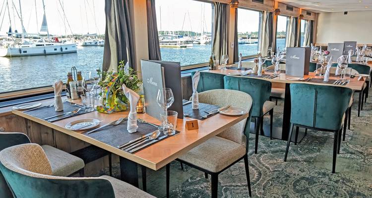 Zone de restauration sur un navire avec vue extérieure sur la marina.