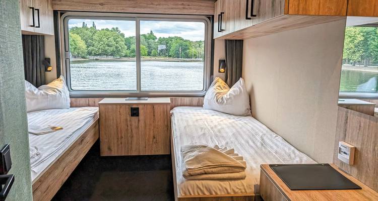 Suite cabine avec lits jumeaux et vue sur l'eau.