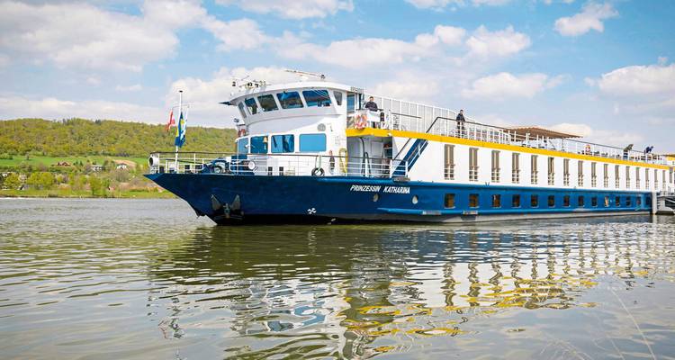 Cruise ship named 'Princessin Katharina' docked at a riverside.