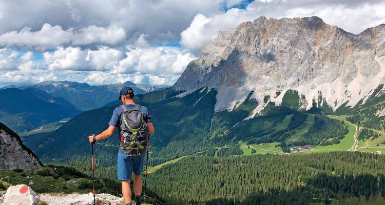 Man hiking in the mountains with green valleys below.