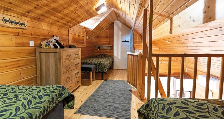 Chambre en bois chaleureuse avec des lits et des peluches.