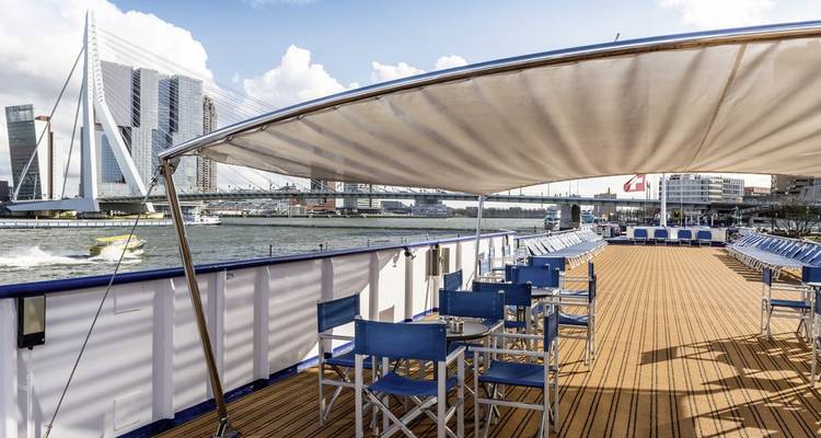 Outdoor seating area on a boat with city skyline.