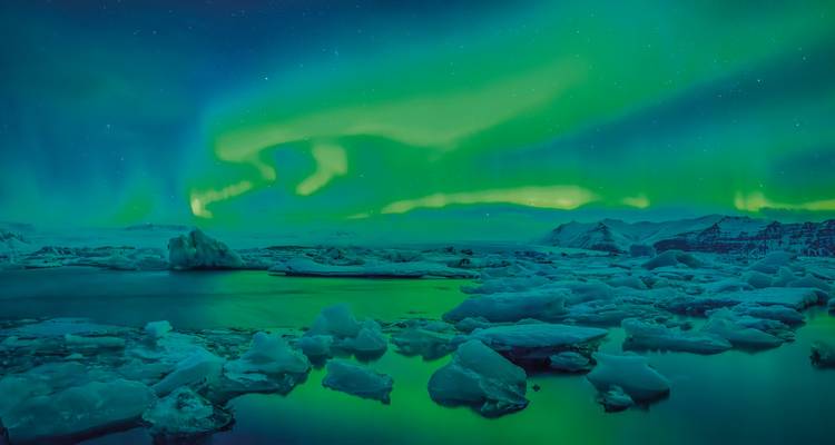 Nordlichter über einer gefrorenen Landschaft mit Eisbergen bei Nacht.