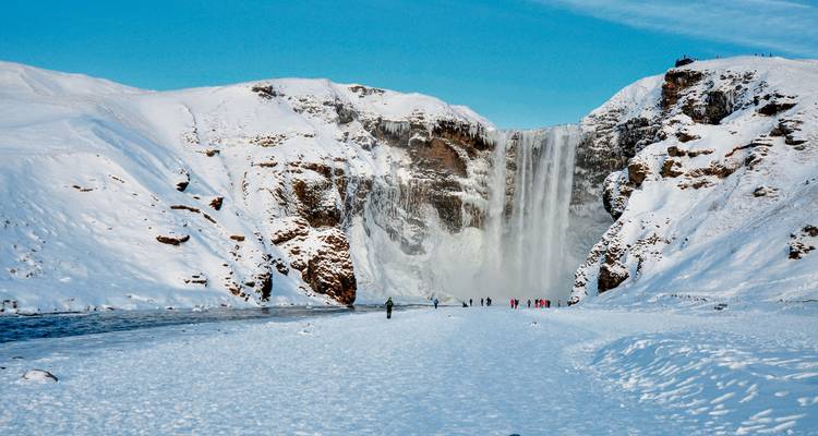 Bevroren waterval omgeven door een met sneeuw bedekt landschap.