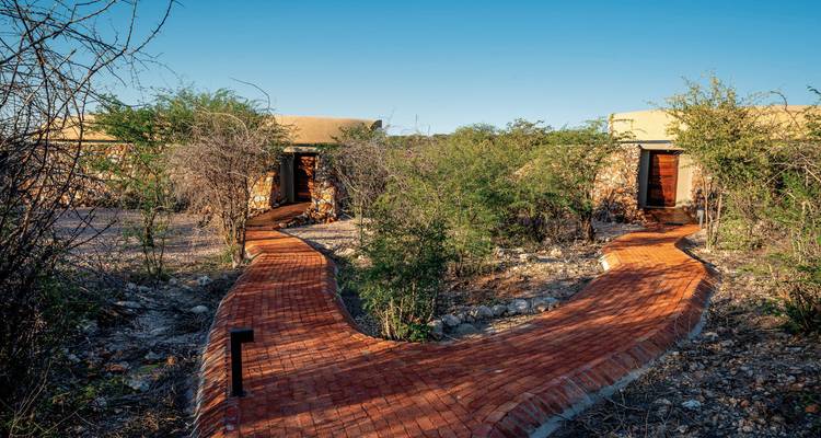 Pathway leading to modern lodges in a desert landscape.