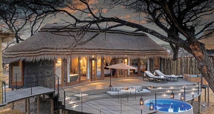 Luxury lodge with a pool and dining setup at sunset.