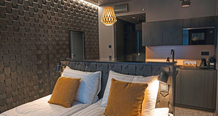 Chambre d'hôtel moderne et confortable avec bois foncé et grand lit.